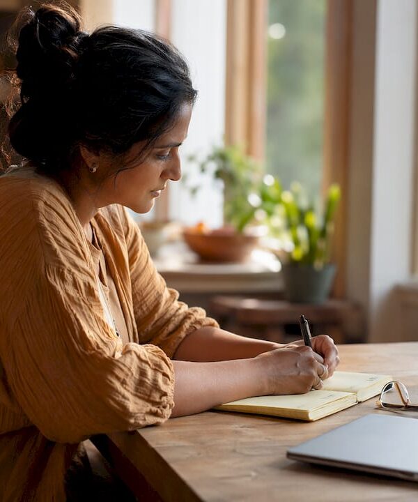 Freelancer writing notes at cozy home desk