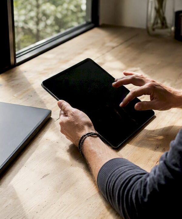 Hands interacting with tablet and notebook on desk
