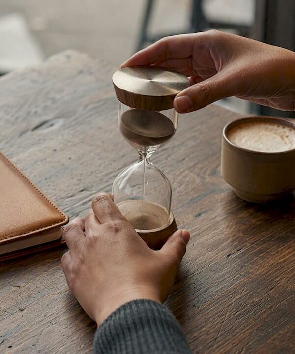 Freelancer hands setting hourglass timer on desk