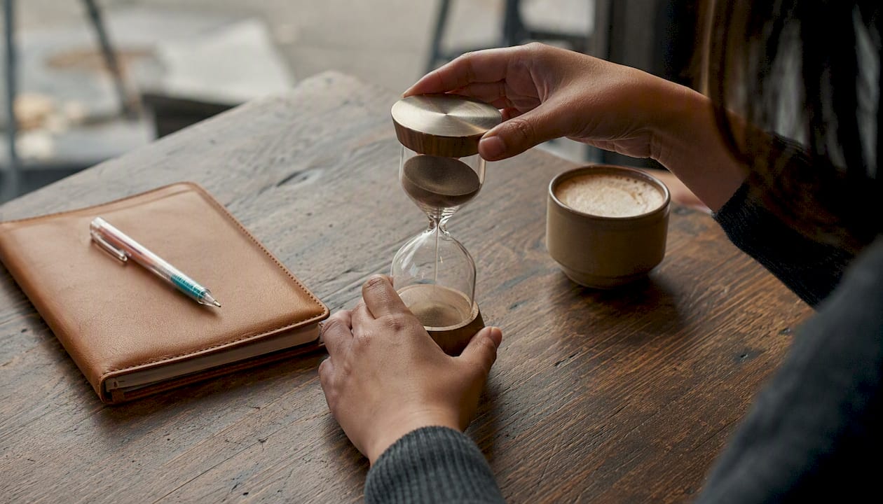 Freelancer hands setting hourglass timer on desk